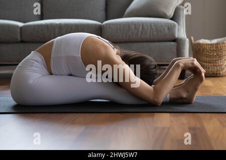 Side view woman in white activewear do Seated Forward Bend Stock Photo