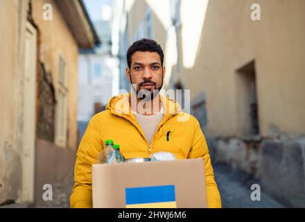 Volunteer cyrrying box with Humanitarian aid for Ukrainian refugees in street Stock Photo