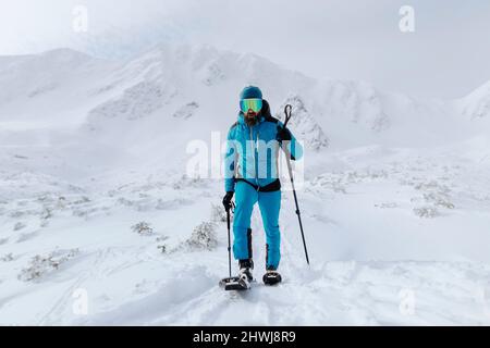 Male backcountry skier hiking to the summit of a snowy peak in the Low Tatras in Slovakia. Stock Photo