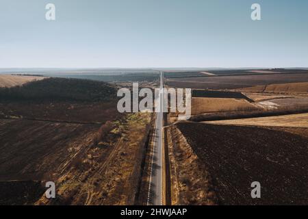 Natural idyllic seasonal autumn background with a straight road going into blue clear sky Stock Photo