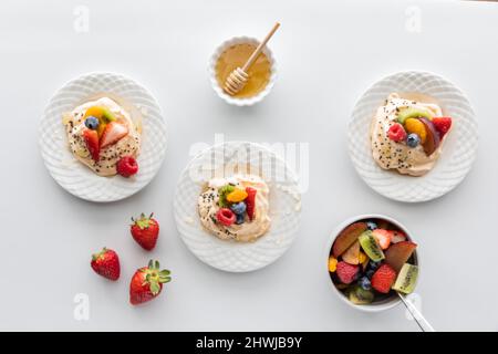 Top down view of homemade meringues topped with fresh fruit and honey. Stock Photo