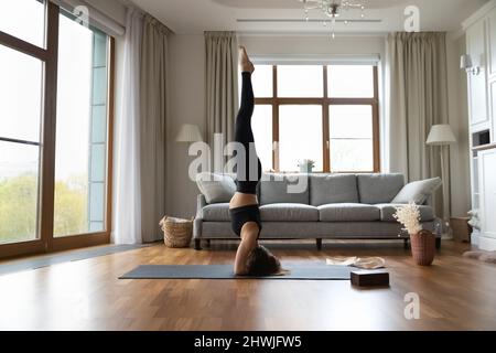 Woman wear black sportswear performs supported headstand or Salamba Sirsasana Stock Photo