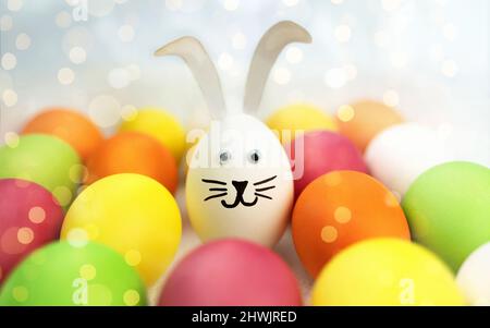 Funny bunny among colorful easter eggs. Background with bokeh Stock Photo