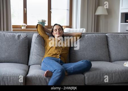 Serene young woman relaxing on couch in cozy living room Stock Photo