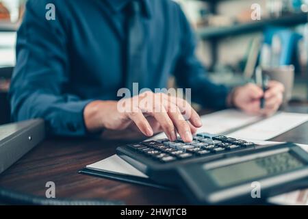 Financial businessman working on desk office using a calculator to calculate calculating corporate income tax data And analyzing charts of financial. Stock Photo