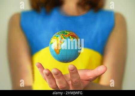 Earth and flag of Ukraine. Woman with globe. Concept of impact of war on world Stock Photo
