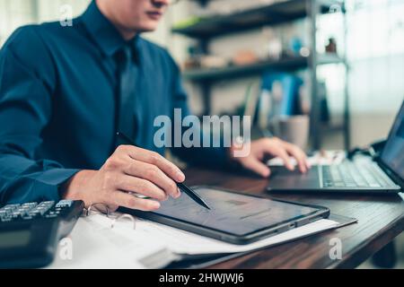 Business hand hold stylus pen touch screen digital tablet with business diagram on the table workspace. Stock Photo