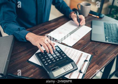 Financial businessman working on desk office using a calculator to calculate calculating corporate income tax data And analyzing charts of financial. Stock Photo