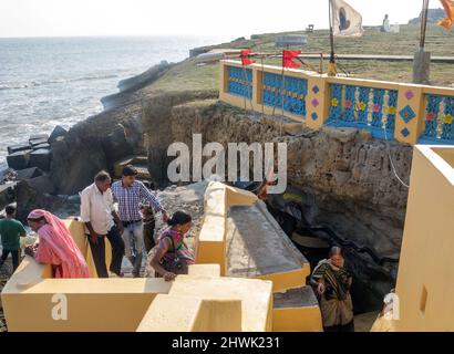 India, Gujarat, Island of Diu. Gangeshwar Mahadev Shiva temple entrance. Shivlingams with food offerings to Shiva washed out by the sea at high tide. Stock Photo