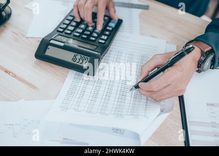 Accountant writing, checking and working on company data, document, report and calculator to calculate  on desk office. Accounting business concept. Stock Photo