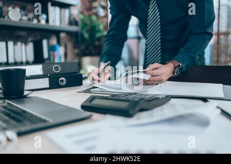 accounting reading report from file folder and financial statement on desk.Accounting woking with data sheet on the office desk. Stock Photo