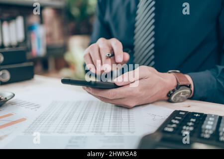 Businessman use cell phone and working on office desk and analyzing new project of accounting finance. Investment, Financial advisor and accounting co Stock Photo