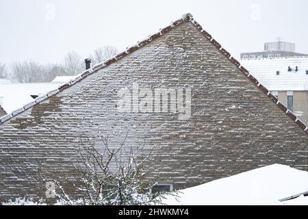 A wall of a house is covered with snow during a blizzard. Textured effect on the wall of a house, caused by blowing snow during a snow storm. Stock Photo