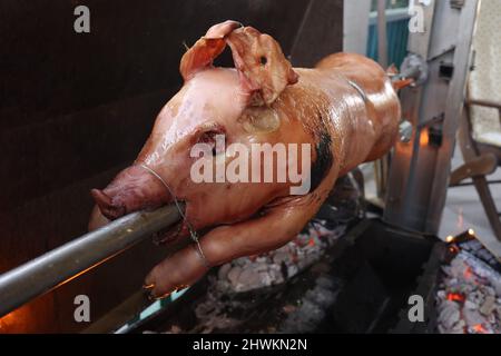 Pig is being grilled slowly on spit in traditional way Stock Photo