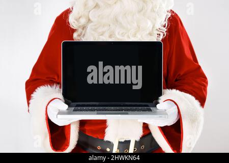 Now you can type your wish list. Cropped portrait of Father Christmas holding a laptop - isolated on white. Stock Photo