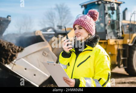 Woman with walkie talky on compost facility dispatching deliveries Stock Photo