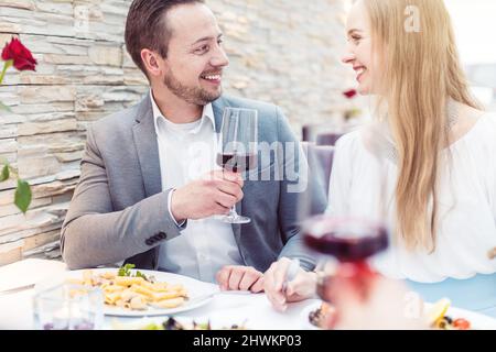 Cheerful people enjoying drink and food in Italian restaurant Stock Photo