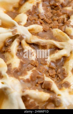 Macro photography of ice cream with caramel. A close-up view of a sweet dessert from above. Abstract food background. Vertical photo Stock Photo