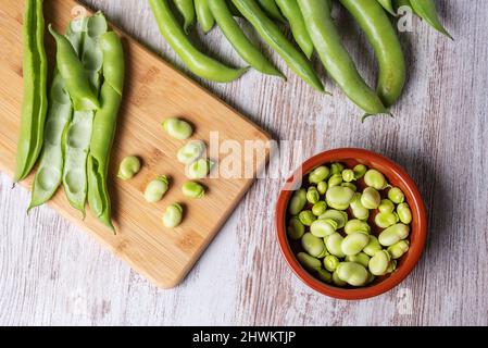 Broad beans on a white wooden table, top view. Stock Photo