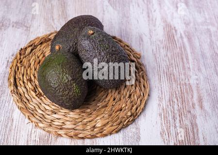 Avocados on a trivet, and on top of a faded white wood table. Stock Photo