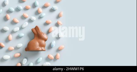 Easter banner with sweets as eggs and chocolate rabbit on blue background. View from above. Flat lay style. Happy Easter greeting card with copy space Stock Photo
