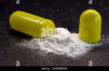 capsules tablets - open white powder sprinkled on black background, macro photo Stock Photo