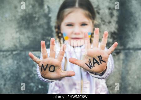 Beautiful and scared child inscription NO WAR on his hands. Russia's invasion of Ukraine, kids against the war Stock Photo