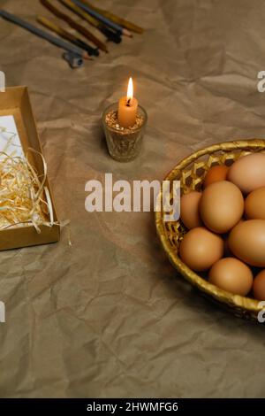 Candle with light. Rustic background. Tools for decorating Paschal eggs, Pysankas. Collection of eggs. Homemade pen for drawing eggs. Preparation for Stock Photo