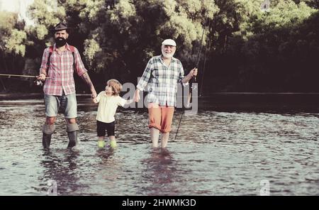 Boy with father and grandfather fly fishing outdoor over river background. Man in different ages. Hobby and sport activity. Stock Photo