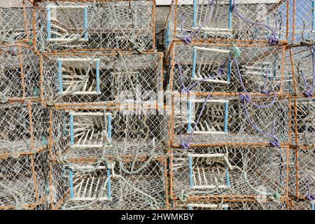 Many lobster and crab creels or pots piled on the beach at Hastings, East Sussex, UK, awaiting deployment under the waves. Stock Photo