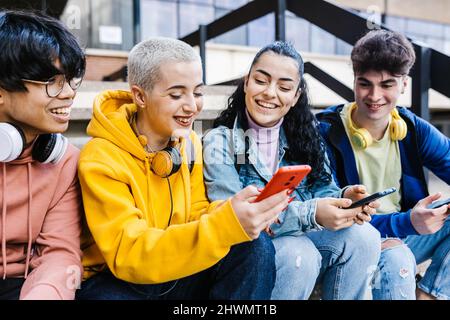 Group of multiracial teenage students using mobile phones on school Stock Photo