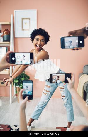 Lets do something fun with todays blogpost. Shot of a beautiful young woman having her picture taken on multiple phones. Stock Photo