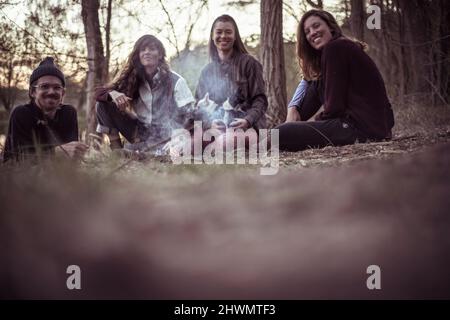 happy friends with dogs in nature sit by fire Stock Photo