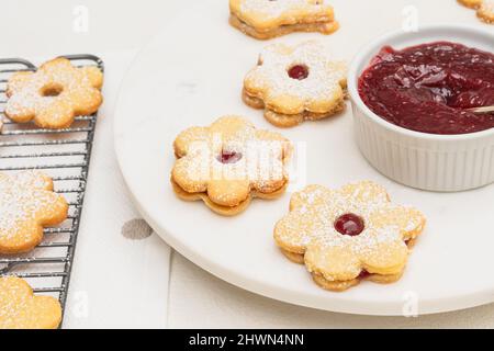 Flower shaped shortbread cookies filled with raspberry jam close up on white background Stock Photo