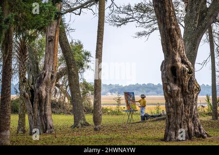 Artist plein air painting on the grounds of Kingsley Plantation along the tidal salt marsh of the Fort George River in Jacksonville, Florida. (USA) Stock Photo