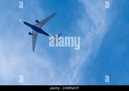 Delta Air Lines passenger jet flying directly overhead beneath a blue sky with white clouds. (USA) Stock Photo