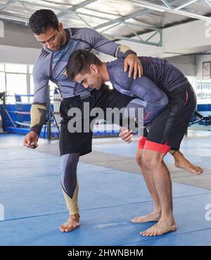 Attack and counter. Full length shot of a jiu jitsu sensei sparring with one of his students during a class. Stock Photo