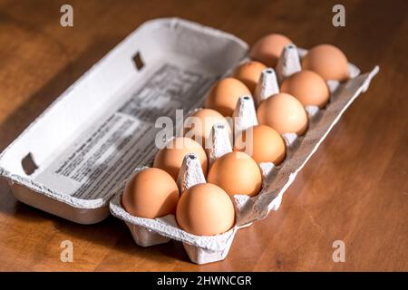 Chicken eggs in carton box on wooden table Stock Photo