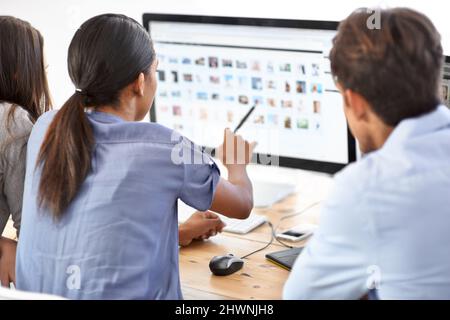 Working together to meet your design needs. Three young editors looking at photos in their office. Stock Photo