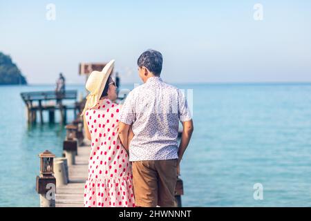 Middle aged couple relaxing on wooden pier in holiday at koh kood ,Thailand. Stock Photo