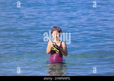 Senior asian woman with a mask for snorkeling in the sea. Stock Photo