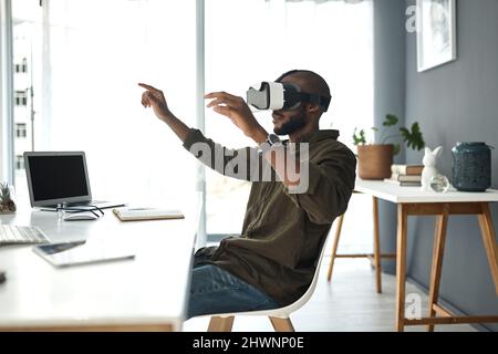 Tomorrows world is created today. Shot of a young businessman using a virtual reality headset in a modern office. Stock Photo