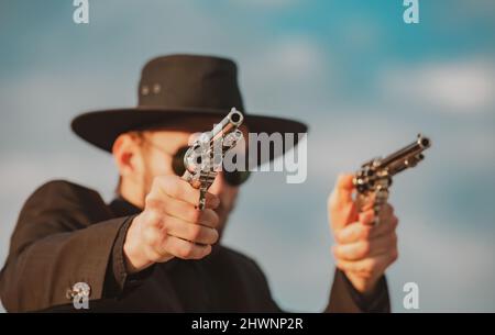 Sheriff in black suit and cowboy hat shooting gun, close up western portrait. Wild west, western, man with vintage pistol revolver and marshal Stock Photo