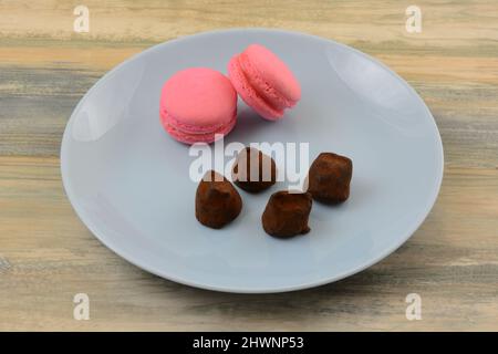 Raspberry macaron flavored truffles with raspberry macarons on blue snack plate Stock Photo