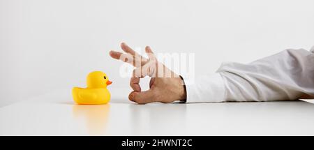 Job dismissal, unemployment or being fired from a work concept. Businessman hand is about to flick the rubber duckling. Stock Photo