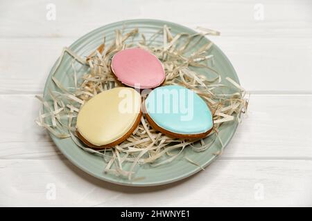 Delicious cookies with colorful glaze on a plate on white wood . Stock Photo