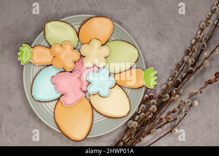 Easter cookies on plate and willow branches on grey background. Stock Photo