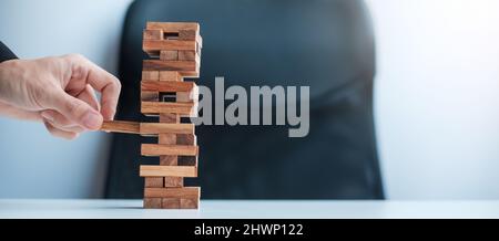 Businessman hand placing or pulling wooden block on the tower. Business planning, Risk Management, Solution and strategy Concepts Stock Photo