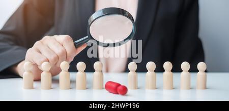 Businesswoman hand holding magnifying glass for recruiting leader man wooden from crowd of employees.Human resource management, Recruitment, Teamwork, Stock Photo