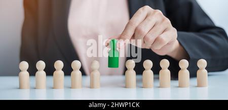 Businesswoman hand pulling leader man wooden from crowd of employees. Toxic People, Human resource management, Recruitment, Teamwork and leadership Co Stock Photo